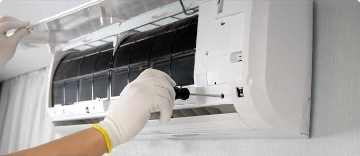 Gloved technician servicing the filter area of an indoor wall-mounted air conditioner